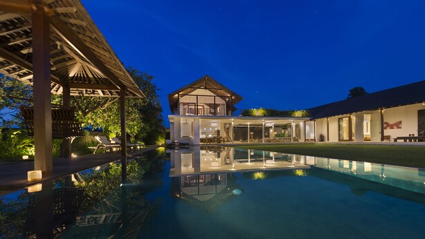 A modern resort with a swimming pool, a covered outdoor area, and a well-lit building with a balcony. - Villa Kavya (Canggu)