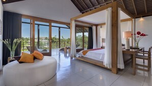 A spacious bedroom with a large bed, a sitting area, and a view of the outdoors. - Villa Kavya (Canggu)