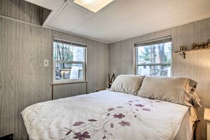Relax in this serene bedroom with a large bed, flanked by two windows and a shelf above.