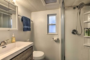 Bathroom features a sink, mirror, toilet, and shower area.