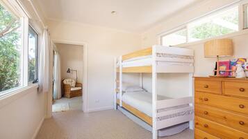 Cozy bedroom with a bunk bed, wicker chair, and dresser.