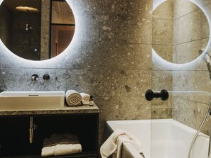 A bathroom with a bathtub, a sink with a mirror, and a towel rack. - Peterhof Chalets (Zwischenwasser)