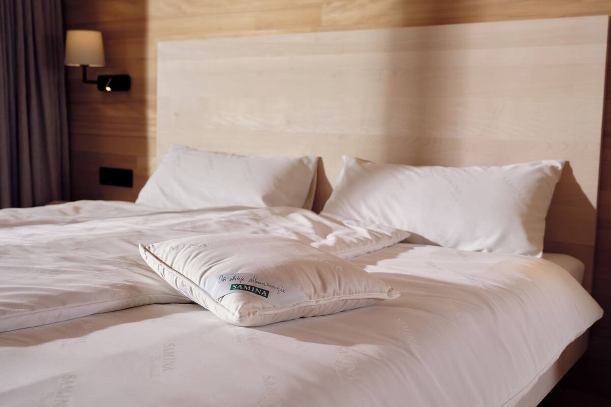 Una habitación de hotel con una cama bien hecha, cabecera y una lámpara fijada a la pared.
