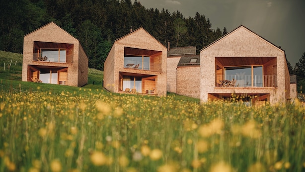 A modern house with a flat roof, wooden balconies, and a large window. - Peterhof Chalets (Zwischenwasser)