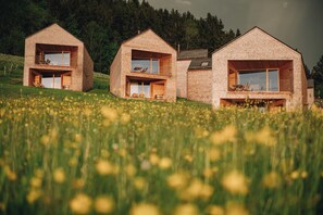 A modern house with a flat roof, wooden balconies, and a large window. - Peterhof Chalets (Zwischenwasser)