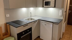 A compact kitchen with a sink, microwave, oven, and dishwasher. - Quiet studio for 4 pers. with terrace in Samoëns (Samoëns)
