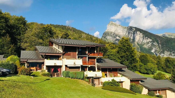 A multi-story chalet with a balcony, set in a mountainous area with a clear sky. - Quiet studio for 4 pers. with terrace in Samoëns (Samoëns)