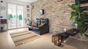 A modern living room with a stone wall, a leather sofa, a patterned rug, and a fireplace.