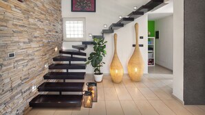 A modern staircase with a stone wall on one side and a green room on the other.