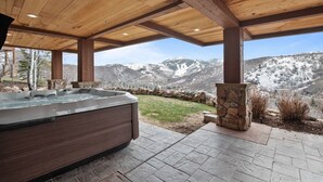 Una vasca idromassaggio sotto un pergolato di legno con vista sulle montagne.