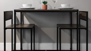 A dining table with two chairs, a potted plant, and two wine glasses.