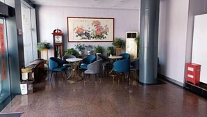 A lobby with a large clock, framed artwork, and several seating areas with blue chairs. - Chaohu Zhongxin Business Hotel (Chaohu)