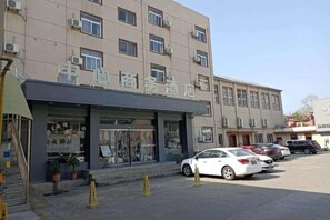 Un bâtiment sur lequel on peut lire l’inscription « Hôtel », et un parking où sont garées plusieurs voitures.