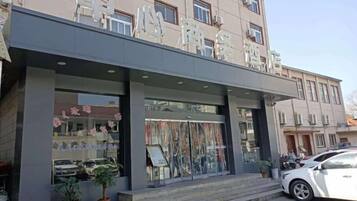 A building with a storefront, large windows, and a car parked in front.