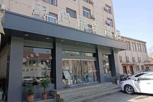 Un edificio con escaparate, grandes ventanales y un coche estacionado adelante.