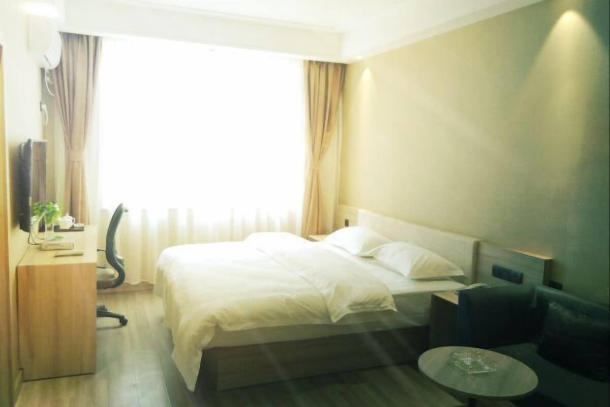 Une chambre d’hôtel équipée d’un lit, d’un bureau, d’une chaise, d’une petite table et d’un téléviseur.