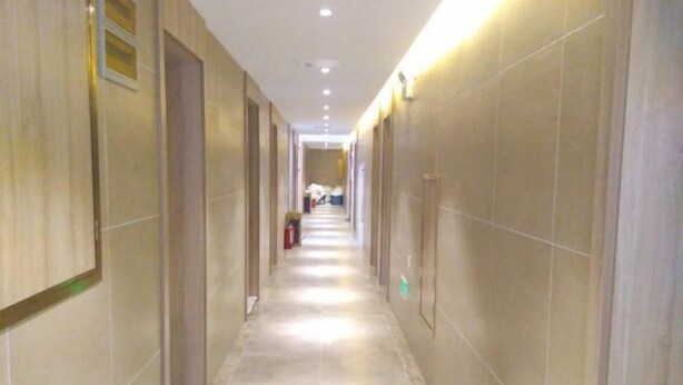 A long, narrow hallway with tiled walls and a light-colored floor, leading to a room at the end. - Chaohu Zhongxin Business Hotel (Chaohu)