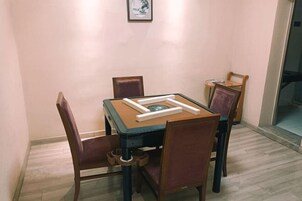 Un comedor con una mesa y cuatro sillas, un cuadro en la pared, y una puerta que da a otra habitación.