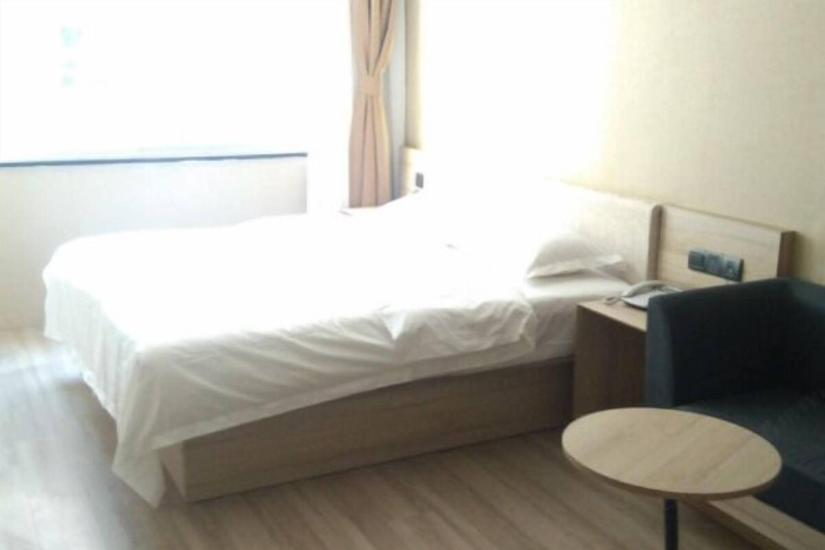 Une chambre d’hôtel avec un lit, une table de chevet, une chaise et une petite table ronde.