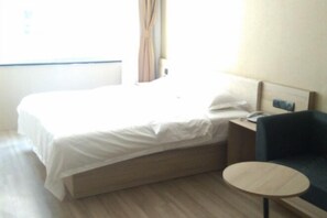 A hotel room with a bed, a bedside table, a chair, and a small round table. - Chaohu Zhongxin Business Hotel (Chaohu)