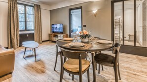 A modern dining area with a round table, chairs, and a television in the background. - Majestic Broadway - 4 star apartment with spectacular views (Chamonix-Mont-Blanc)