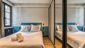 A hotel room with two beds, a large mirror, and a window with curtains. - Majestic Broadway - 4 star apartment with spectacular views (Chamonix-Mont-Blanc)