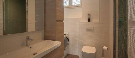 Une salle de bain moderne avec un grand lavabo, des toilettes et un espace douche.