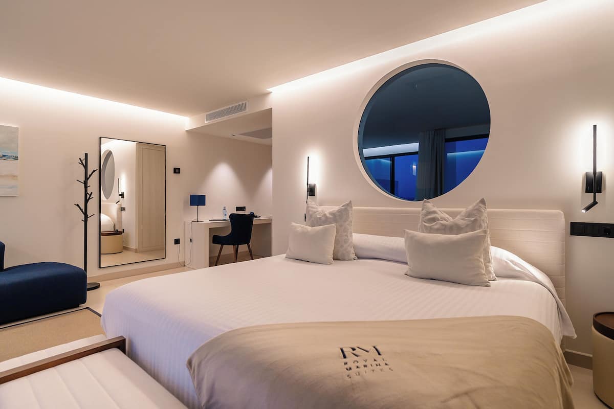 Una habitación de hotel moderna con una cama grande, un escritorio y un espejo redondo.