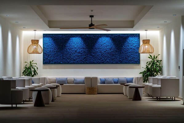 Un área de descanso moderna con una pantalla grande montada en la pared, asientos cómodos e iluminación ambiental.
