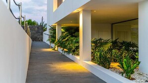Um edifício moderno com um caminho estreito ladeado por paredes brancas e plantas.