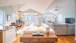 A spacious living area with a dining table, a gray sofa, and a TV. - Fresh and Salty (Carolina Beach)