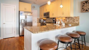 A kitchen with a central island, stainless steel appliances, and wooden cabinets. - Fresh and Salty (Carolina Beach)