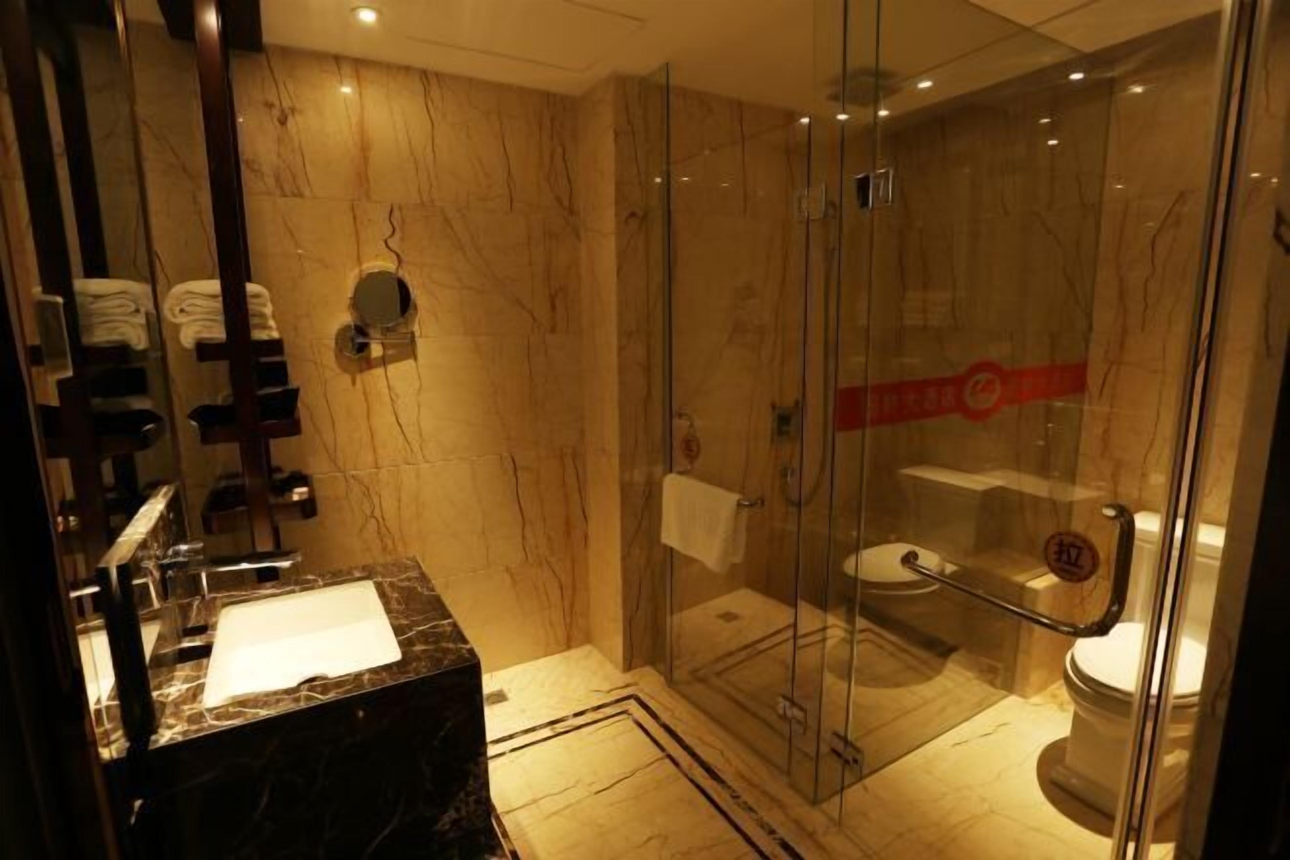 A modern bathroom with a glass-enclosed shower, a marble sink, and a toilet.