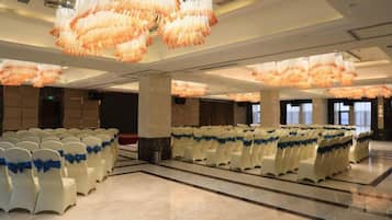 A spacious hall with rows of white chairs, large chandeliers, and a polished floor.