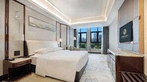 Una habitación de hotel moderna con una cama grande, un escritorio, un televisor y vistas a la ciudad.