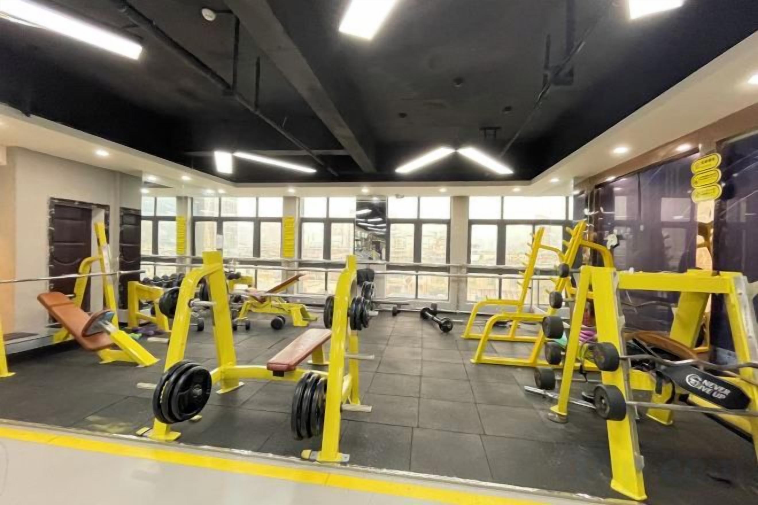 A gym with weightlifting equipment, benches, and dumbbells.