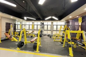 Un gimnasio con equipo de levantamiento de pesas, bancos y mancuernas.