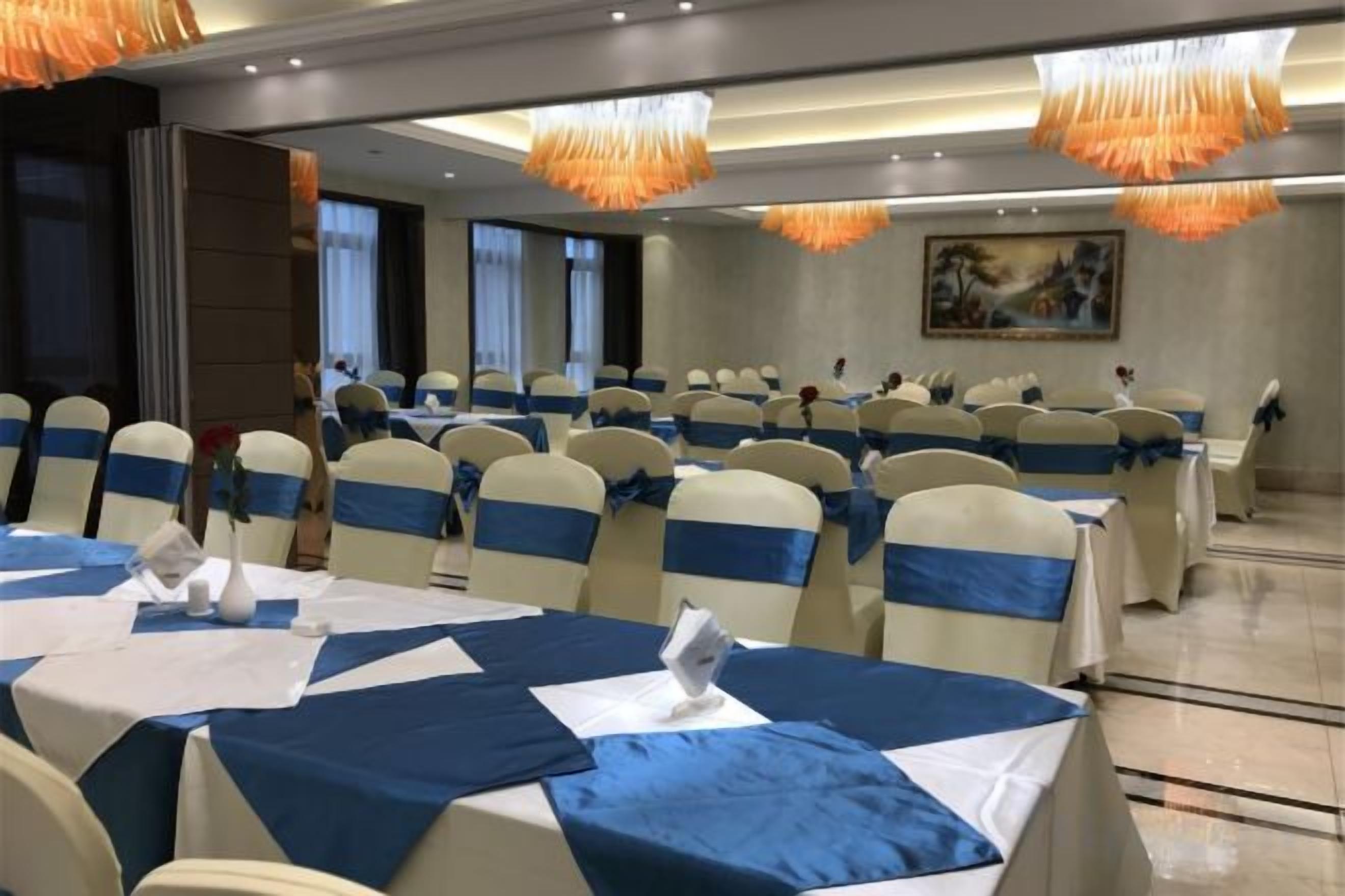 A banquet hall with round tables, chairs, and a chandelier.
