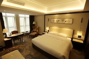 A hotel room with a large bed, a desk, a chair, and a small table. - Yuanlin Hotel (Tongzi County)