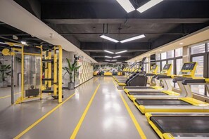 Un gimnasio con cintas de correr, máquinas de pesas y equipo de ejercicio.