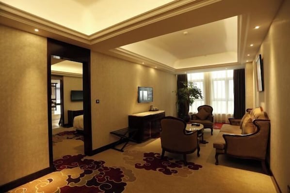 A hotel room with a sofa, armchairs, a small table, a TV, and a desk with a computer. - Yuanlin Hotel (Tongzi County)