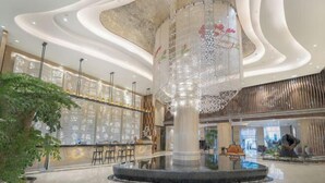 Un moderno vestíbulo con una columna central, zona de estar y una fuente decorativa.