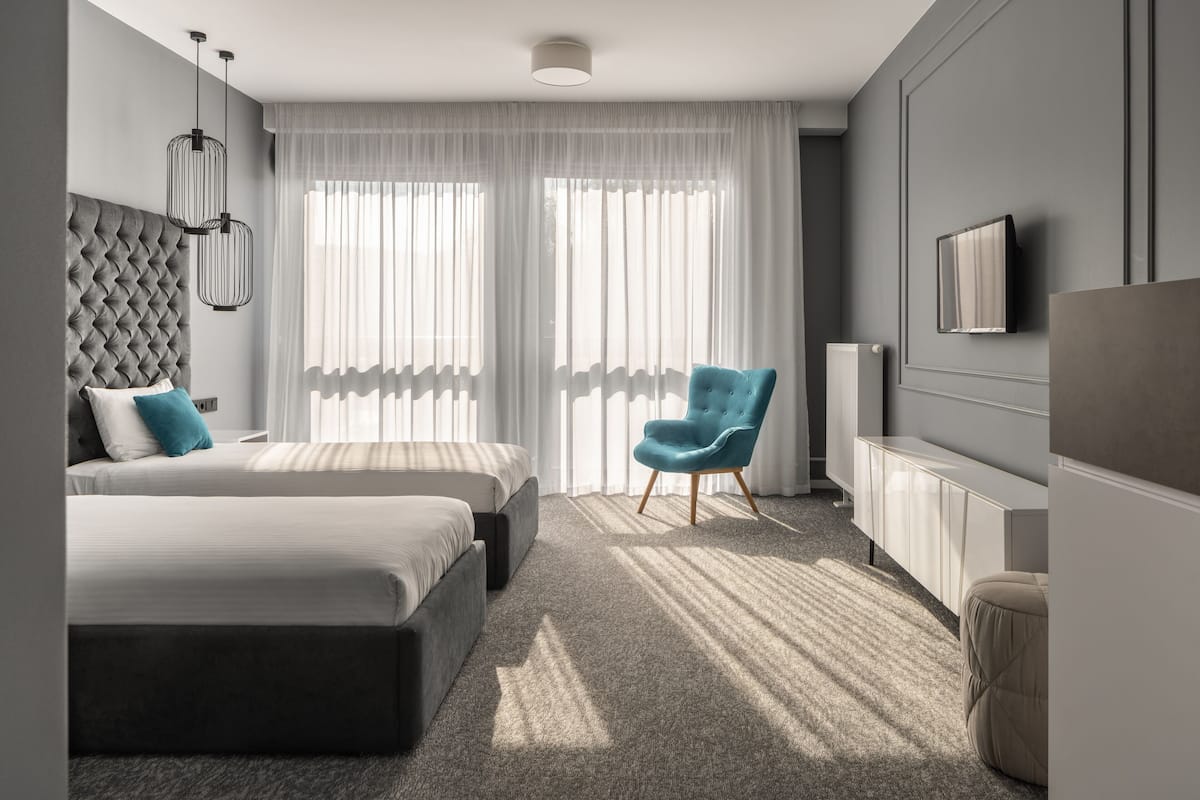 Habitación de hotel moderna con una cama grande, una zona de estar con una silla y un televisor montado en la pared.