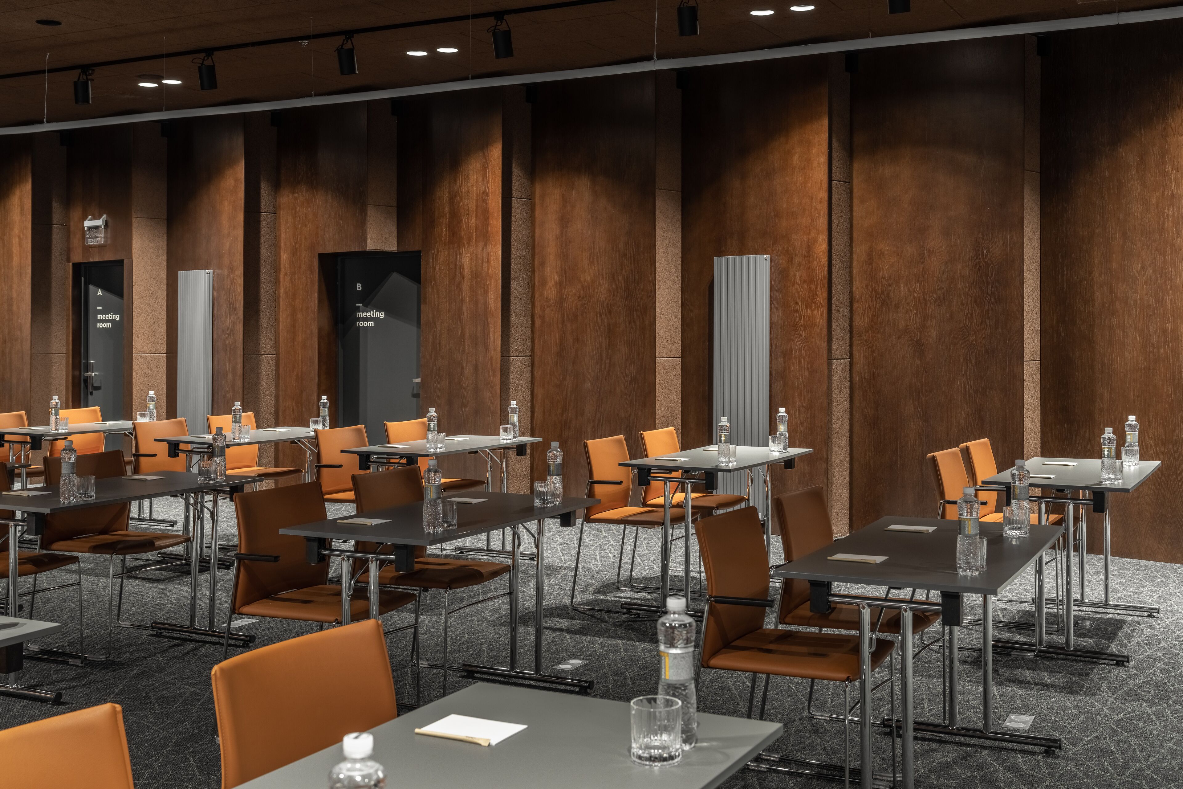 A conference room with tables and chairs, equipped with water bottles and glassware.