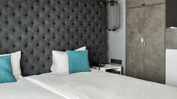 A modern bedroom with a tufted headboard, a white bed, teal and white pillows, a bedside table with a lamp, and a wardrobe.