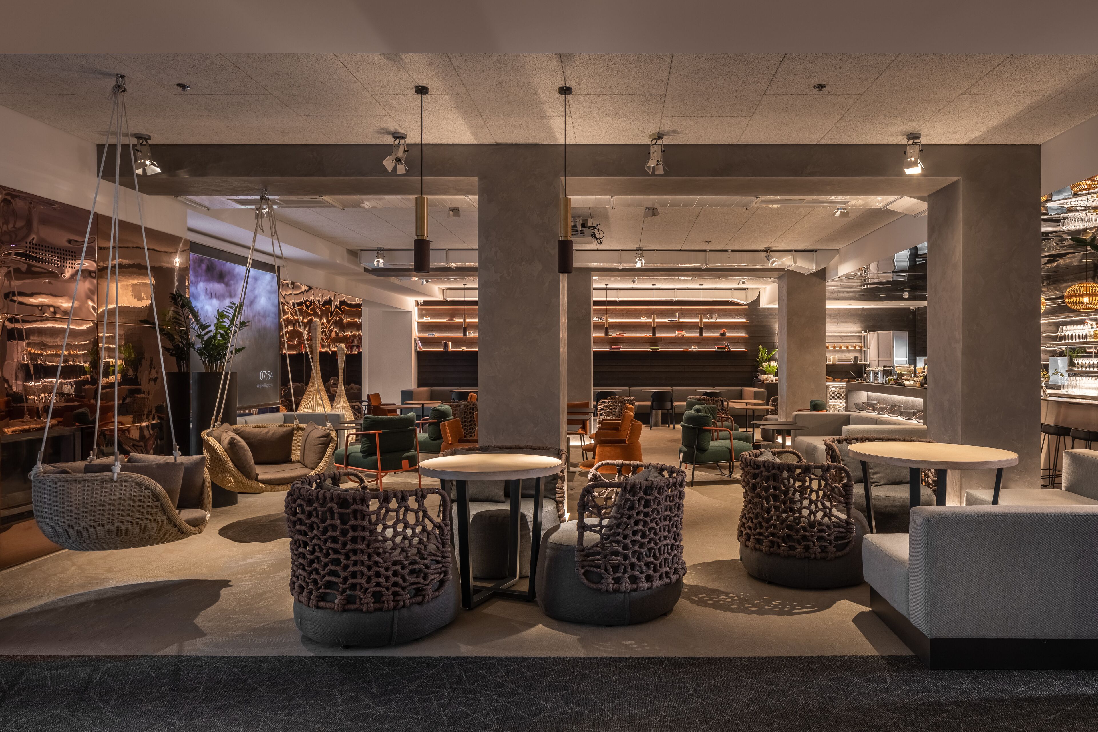 A modern interior with hanging chairs, round tables, and a bar area.