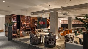 Un área de estar moderna con asientos, el logo de Netflix y una estantería al fondo.