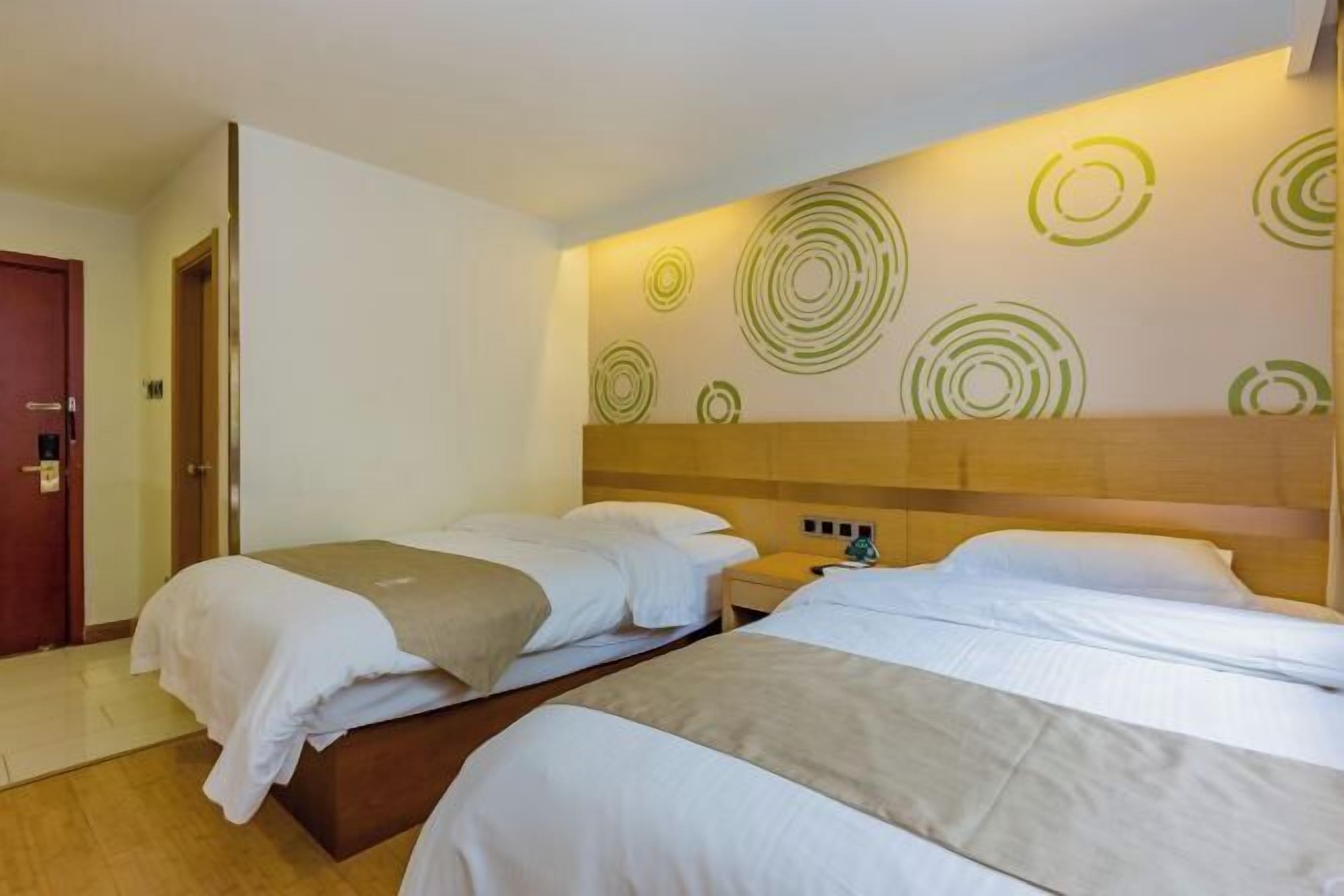 A hotel room with two beds, a wooden headboard, and a wall with circular patterns.