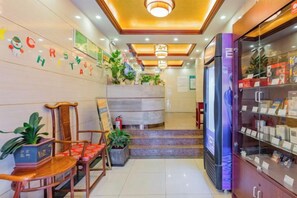 A hotel lobby with a reception desk, seating area, and a display cabinet.