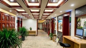 A hotel corridor with a patterned carpet, wooden paneling, and a reception desk with a computer. - GreenTree Inn (Beijing Hospital of Traditional Chinese Medicine, Nanluogu Lane, Houhai) (Beijing)